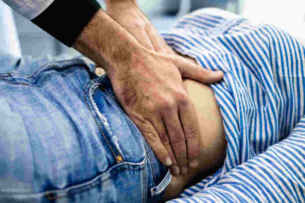 Medical staff touches patient's abdomen to examine. Medazur Medical Clinic in Leytonstone.