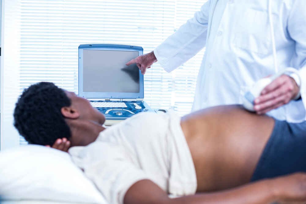 Male doctor explains about abdominal ultrasound to female patient. Medazur Medical Clinic in Leytonstone.